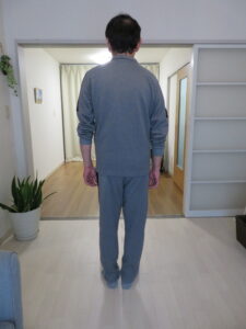 頭部はやや前方に突出し、肩は前方に巻き込み気味で肩甲骨外転傾向。胸椎は軽度後弯し、猫背姿勢が認められる。骨盤は中間位で安定し、両足は均等に接地。全体として日常的な立位姿勢だが、前傾・猫背傾向があり、姿勢改善や整体・ストレッチによる調整が有効