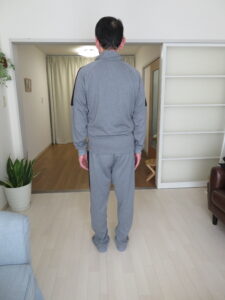 整体施術後の人物の後ろ姿。頭部前方突出が改善し、頸椎の自然なカーブが保たれている。肩甲骨は内転し、胸椎後弯が軽減して猫背姿勢が改善。骨盤は中間位で安定し、両足は均等に接地。全体として背骨のアライメントが整い、安定した立位姿勢が確認できる。整体・姿勢改善・猫背矯正の効果を示す専門的な姿勢分析。